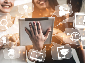 Lachende Personen schauen auf ein Tablet. Rund um das Tablet sind Symbole angeordnet.