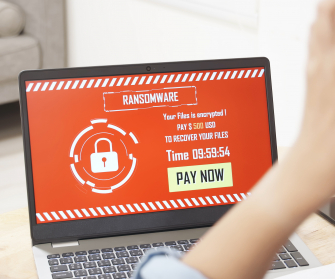 Ransomnote auf Bildschirm von Laptop mit verzweifeltem Mensch