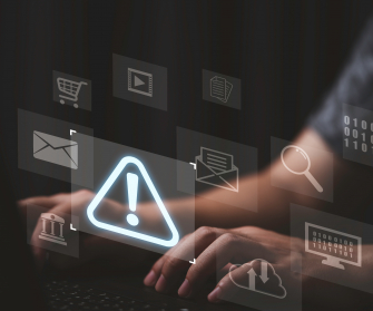 Ausrufezeichen schwebt über PC an dem Hände tippen