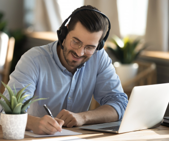 Mann mit Headset sitzt im Home-Office vor seinem Laptop