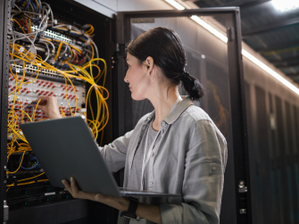 Mensch arbeitet an Serverschrank mit gelben Kabeln