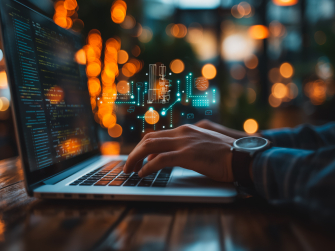 Person sitzt am Laptop, im Hintergrund befinden sich abstrakte Linien und Symbole